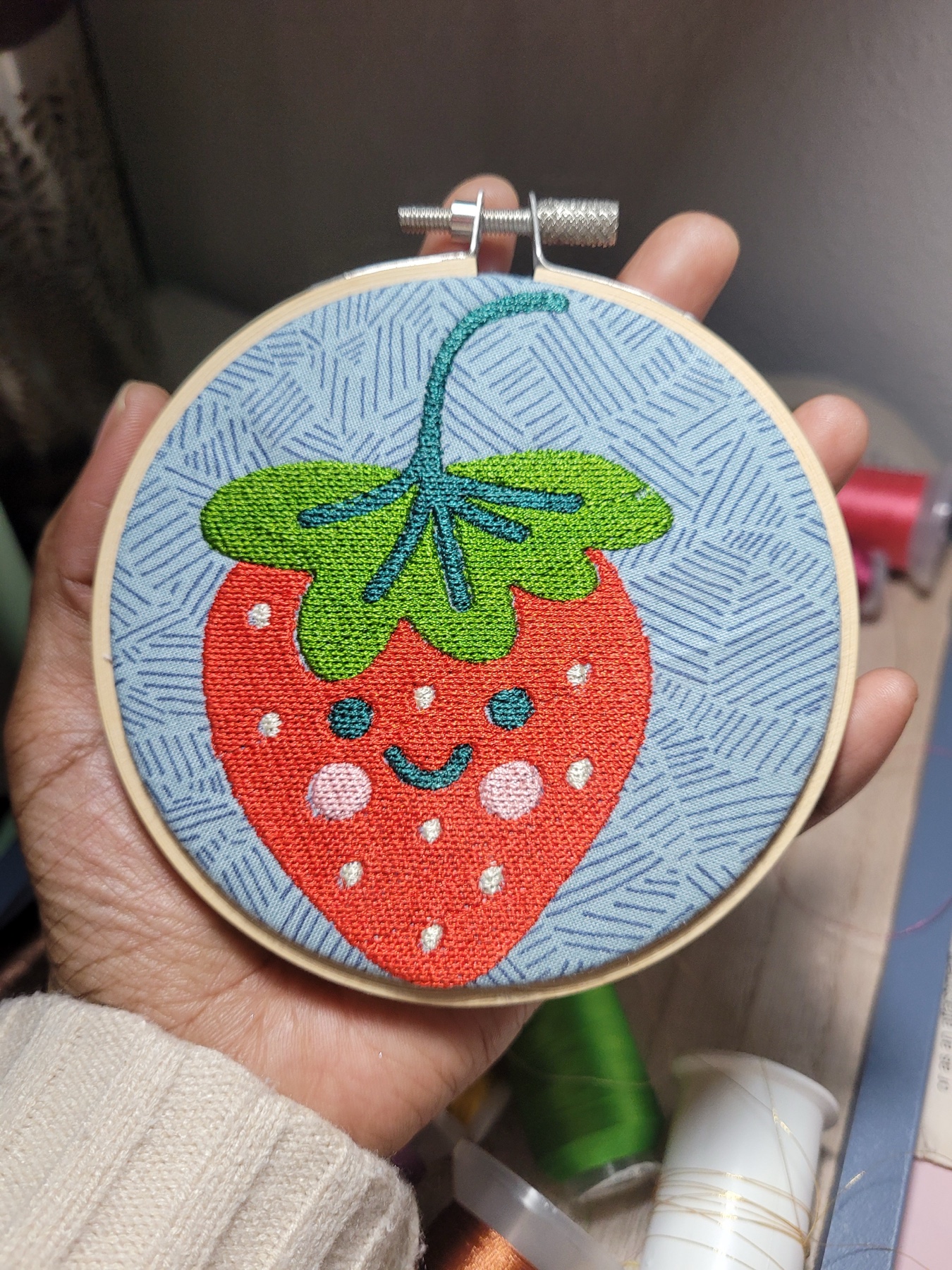 A strawberry design stitched in an embroidery hoop
