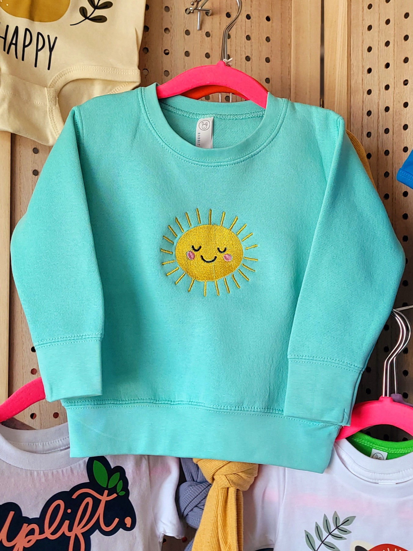 Radiant Glow Sun embroidery stitched onto an aqua sweatshirt